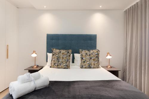 开普敦The Cosmo Luxury Suites by Totalstay的一间卧室配有一张带两盏灯的大型白色床。