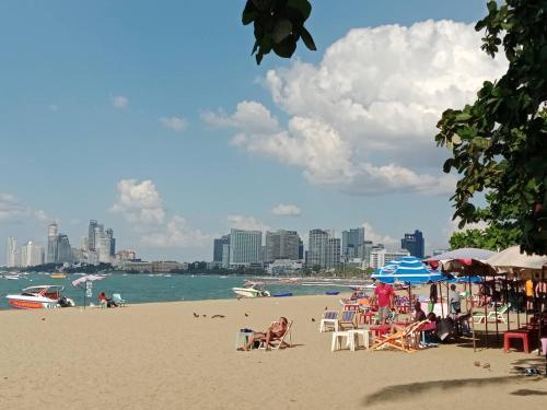 芭堤雅市中心The One Hotel的海滩上有人坐在椅子和遮阳伞上