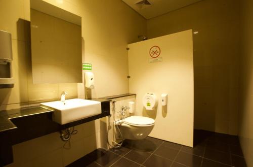 当格浪Digital Airport Hotel的一间带卫生间、水槽和镜子的浴室