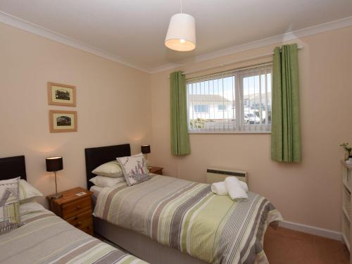 Marhamchurch2 Bed in Widemouth Bay 40636的一间卧室设有两张床,窗户设有绿色窗帘