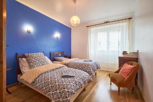 BrézinsChez Emile的一间卧室设有两张床和蓝色的墙壁