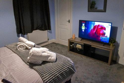 利夫斯登格林Watford Cozy Full Home W Parking - Perfect for Harry Potter Studios!的卧室配有电视,屏幕上放有狗