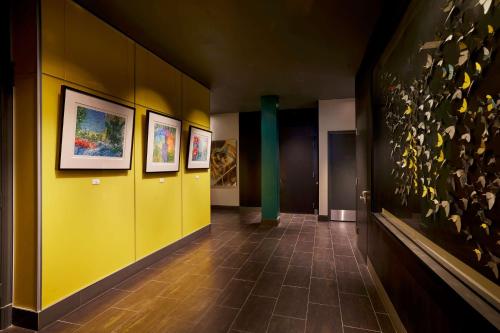 旧金山The Barnes San Francisco, Tapestry Collection by Hilton的走廊上设有黄色的墙壁和墙上的绘画作品