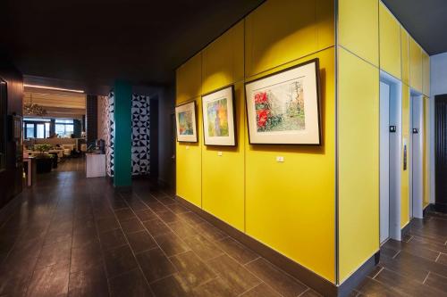 旧金山The Barnes San Francisco, Tapestry Collection by Hilton的走廊上设有黄色的墙壁和墙上的照片