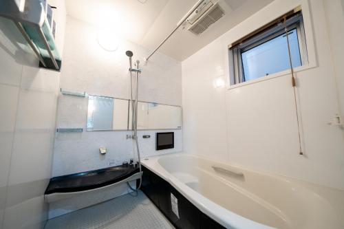 东京Shinokubo guest house的白色的浴室设有浴缸和水槽。
