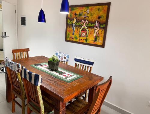 乌巴图巴Apt Familiar-Condomínio fechado UBATUBA的餐桌、椅子和墙上的绘画