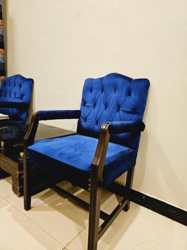 卡拉奇Rose Palace Hotel Karachi的一张蓝色椅子,坐在墙上