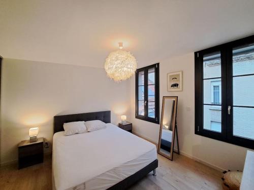 兰斯Antibes, duplex lumineux的卧室配有白色的床和吊灯。