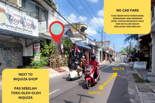 日惹Sante Commune Yogyakarta的骑摩托车沿着城市街道的人