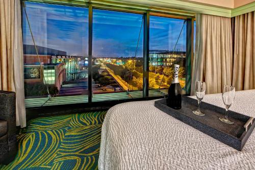 诺福克诺福克奥多明尼奥大学春季山丘套房酒店的带酒杯床和大窗户的客房