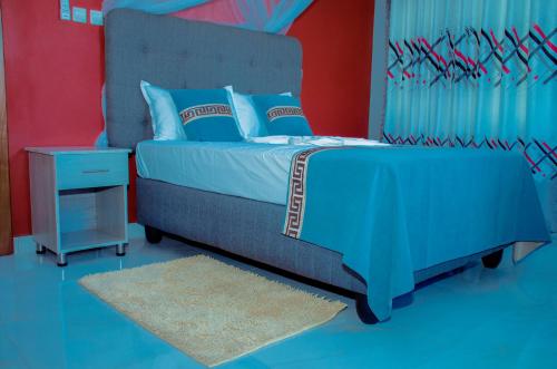 布琼布拉Kinindo Light Hotel的一间卧室设有蓝色和红色的墙壁。