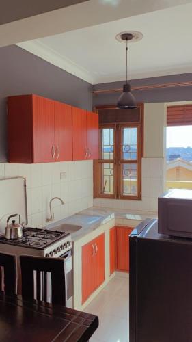 WakisoKamel Furnished Apartments!的厨房配有红色橱柜和炉灶烤箱