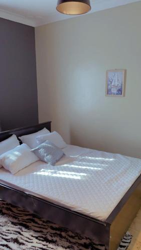 WakisoKamel Furnished Apartments!的卧室内的一张带白色床单和枕头的床