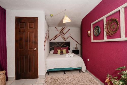 帕纳哈切尔Casa Amaranto的一间卧室配有一张床和粉红色的墙壁
