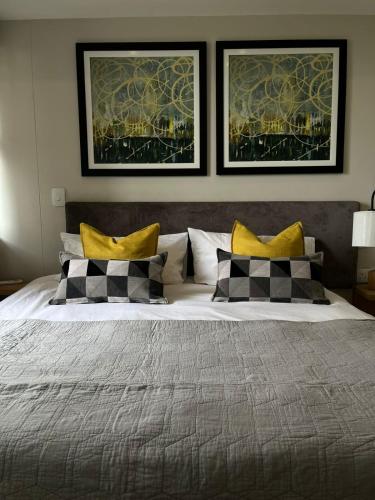 比勒陀利亚REGENCY APARTMENT HOTEL-ST@Y的卧室配有一张大床,墙上挂有两张照片