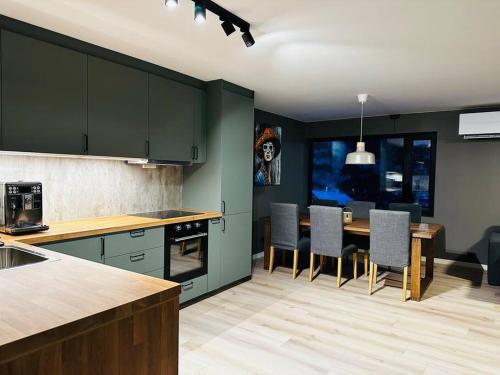 特韦德斯特兰Familievennlig Apartment的厨房配有绿色橱柜和桌椅