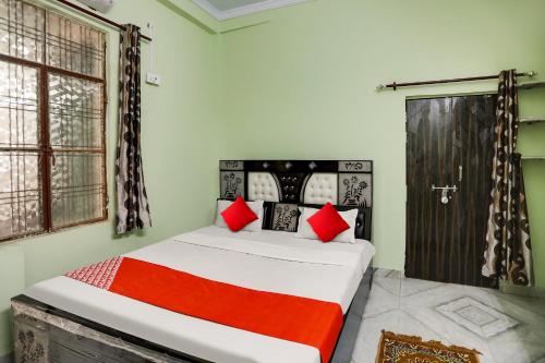 坎普尔OYO Flagship Lucky Hotel的一间卧室配有一张带红色枕头的床和一扇门