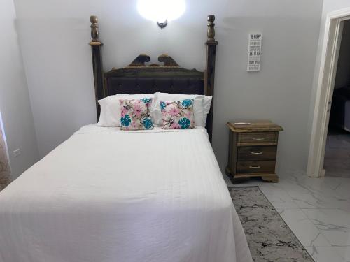 曼米湾MBS Travel Holistic Guest House的一张带白色床单和枕头的床以及床头柜