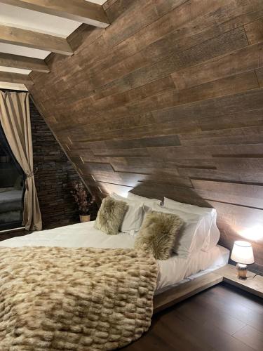 彼得罗沙尼Valea Mosului - Chic A Frame的一间卧室设有一张带木墙的大床