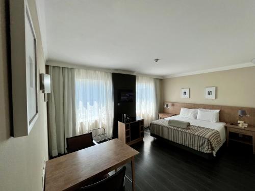 圣保罗Suite executiva reformada dentro do hotel Radisson的配有一张床和一张书桌的酒店客房