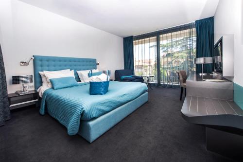 罗维尼阿鲁宾努酒店的一间卧室设有蓝色的床和大窗户