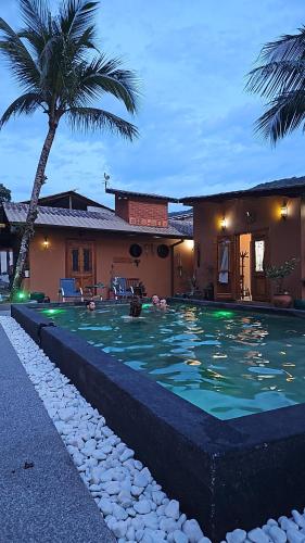 朱奎Hostel Txai Juquehy Suítes的棕榈树屋前的游泳池