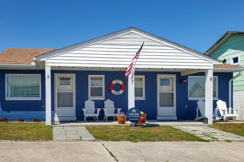 大西洋滩Toes In The Sand的蓝色房子,配有两把草坪椅和一盏美国国旗
