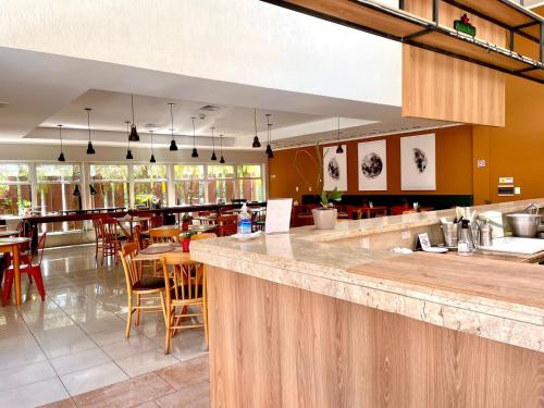 陶巴特Carlton Plaza Baobá的餐厅设有酒吧,配有桌椅