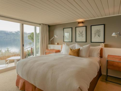 皇后镇Rosewood Matakauri的一间卧室设有一张大床和一个大窗户