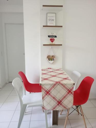 圣若泽-迪里巴马尔Apartamento 1 km da praia do aracagir confortavel的一间用餐室,配有两张红色椅子和一张桌子