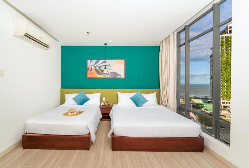岘港May Beach Hotel的绿墙客房的两张床