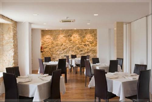 锡古恩萨布兰卡夫人旅馆的一间设有白色桌椅和石墙的餐厅