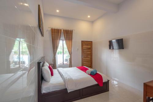 新加拉惹RedDoorz Plus @ Singaraja的卧室配有一张床,墙上配有电视。
