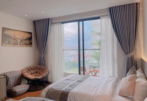 绥和市APEC MANDALA CONDOTEL PHÚ YÊn的一间卧室配有一张床、一把椅子和一个大窗户
