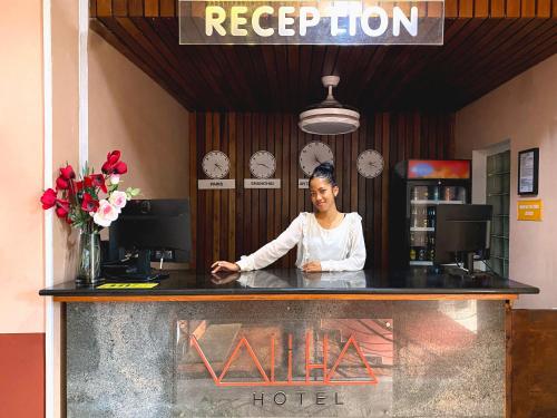 塔那那利佛Valiha Hotel Antananarivo的站在旅馆柜台后面的女人