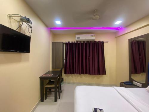 孟买Hotel Royal Grand - Near Mumbai International Airport的客房设有床、书桌和电视。