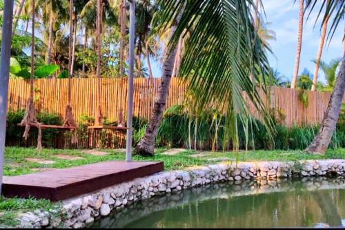 琅勃拉邦Wooden House on lake,city center的一个带池塘、棕榈树和围栏的花园