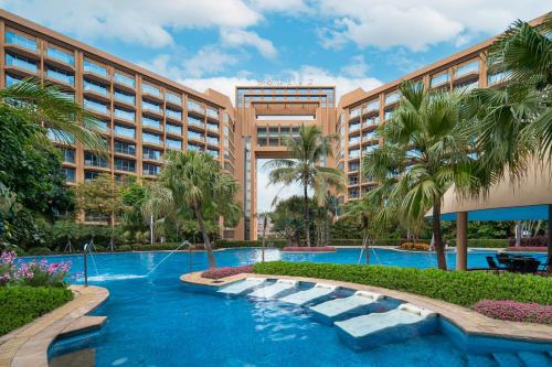东莞东莞帝豪花园酒店的一个带游泳池和棕榈树的度假村