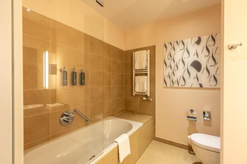 奥拉迪亚奥拉迪亚 希尔顿逸林酒店的带浴缸和卫生间的浴室。