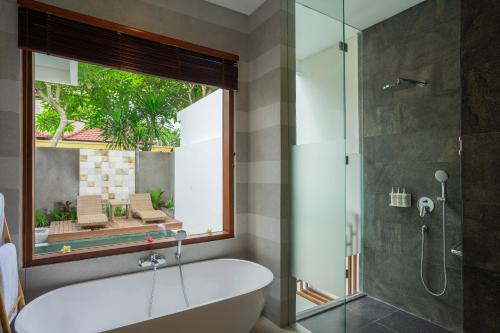 乌布Freddies Villas Ubud Bali的带浴缸和玻璃淋浴间的浴室。