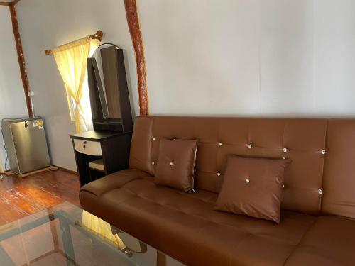 俊穆岛俊穆岛瑞莱克斯海滩旅馆的客厅设有一张棕色沙发,配有电视