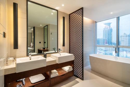 上海上海中星君亭酒店的浴室配有2个盥洗盆、浴缸和大镜子