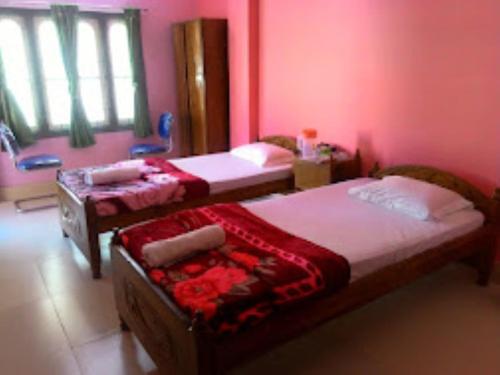 锡尔杰尔Sewak Lodge Silchar的配有粉红色墙壁的客房内的两张床