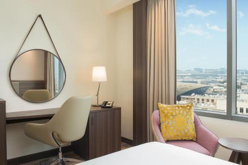 迪拜迪拜机场汉普顿酒店 的酒店客房带镜子和椅子