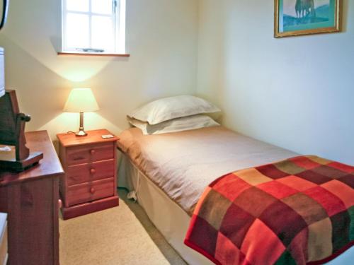 伊尔明顿2 Bed in Stratford-upon-Avon CC025的一间小卧室,配有一张床和一张带台灯的桌子