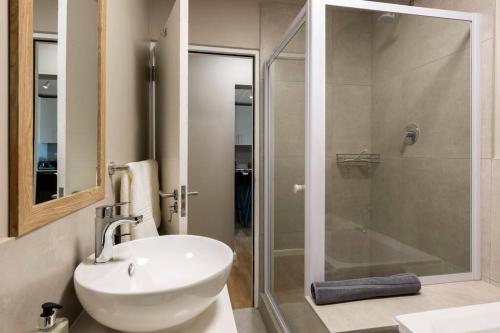 兰格班Nivica 56 Luxury Apartment Langebaan的一间带水槽和玻璃淋浴的浴室