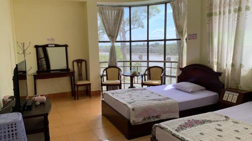 槟知雄王酒店 的一间卧室设有两张床、一张桌子和一个窗口
