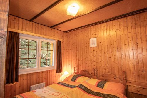 Saas-BalenResidenz Edelweiss SAAS311的卧室配有木墙内的一张床