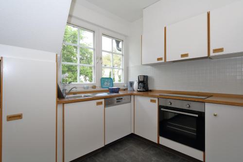 韦斯特兰Südstrand 12的厨房配有白色橱柜和水槽