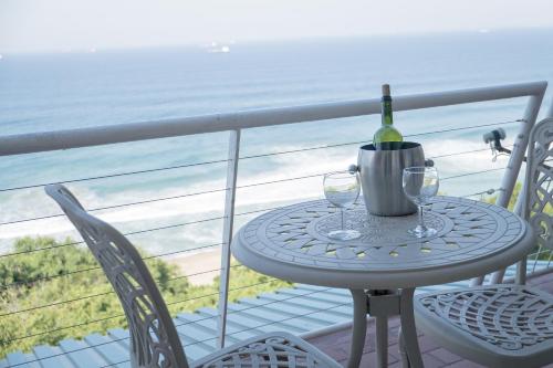 乌姆德洛蒂Sands Beach Breaks Umdloti Beach View的阳台上的桌子上放着一瓶葡萄酒和两杯酒